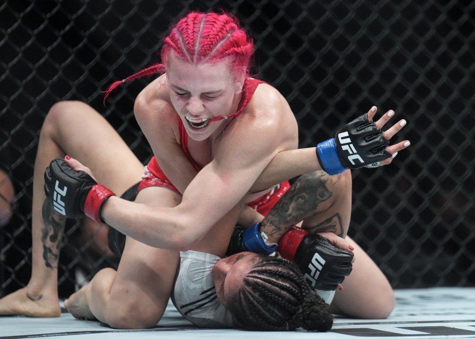 Combate MMA: Luchadora de trenzas rosas y guantes UFC ejecuta sumisión a su rival en el suelo, mostrando gran esfuerzo.
