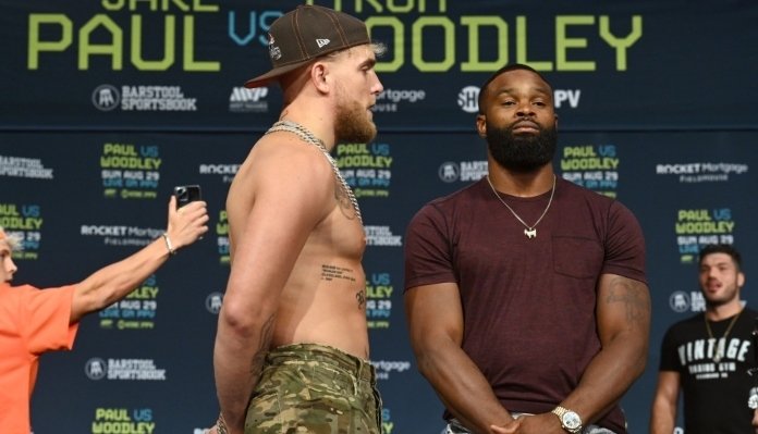 Jake Paul (sin camiseta y gorra) y Tyron Woodley (camiseta granate) se encaran en el pesaje de boxeo.
