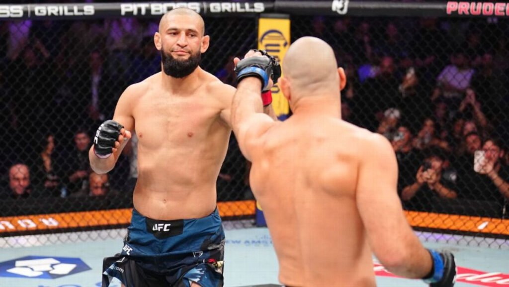 Khamzat Chimaev y Sean Strickland chocando guantes al inicio de su combate UFC. Fondo con público.
