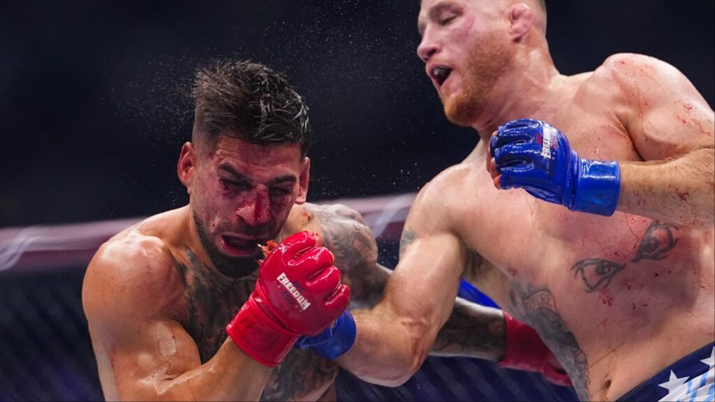 Intenso combate MMA: Luchador con guantes rojos y cara ensangrentada recibe un potente puñetazo de su oponente con guantes azules.