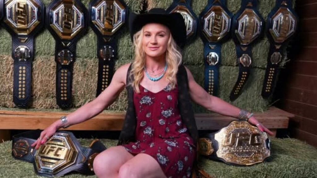 Valentina Shevchenko, campeona UFC con vestido floral y sombrero vaquero, posa con 8 cinturones sobre heno.